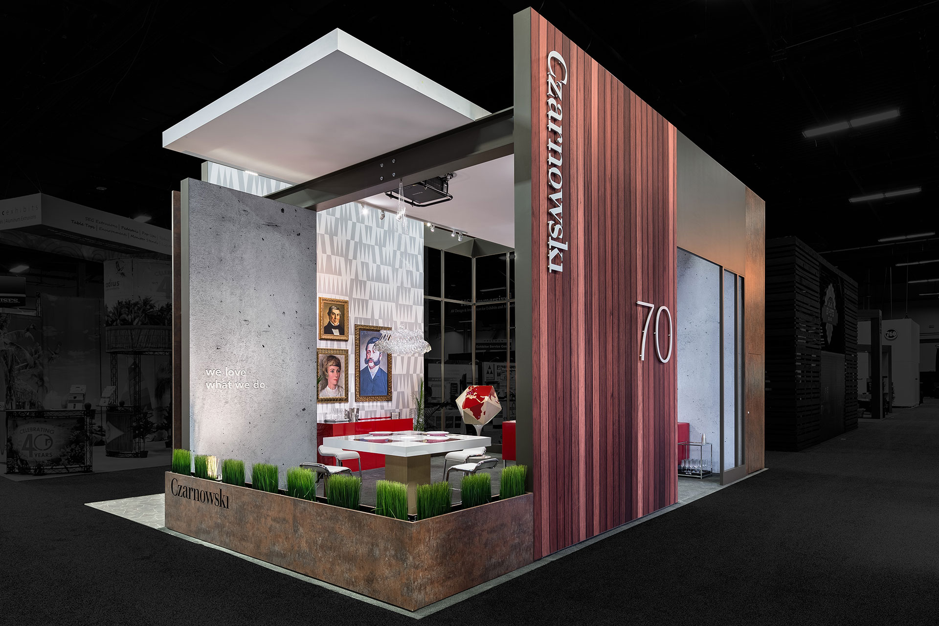 Czarnowski trade show exhibit with a wood-paneled exterior and low decorative planter as an exterior border with classical art on a wall in the background and edited so that the outside area is darkened and colorless.