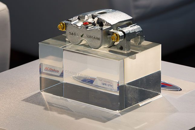 An ACDelco caliper atop a solid transparent cube resembling glass with the ACDelco logo and part numbers etched into the cube.