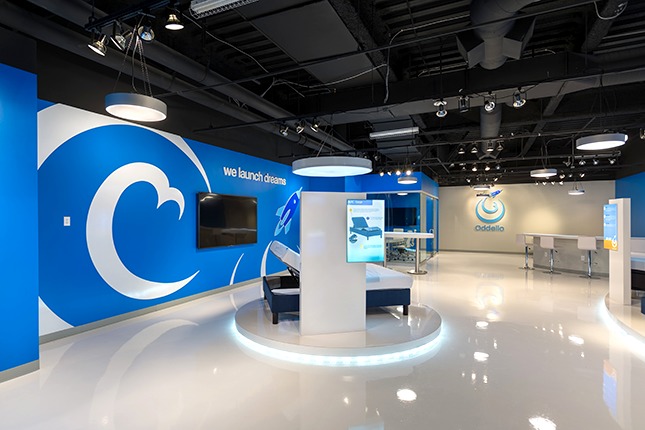 A modern retail space with blue walls and white swirling graphics on the left with a pedestal centered in the frame on shiny white floors.