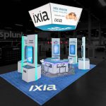 Elevated perspective of Ixia tradeshow exhibit with a white and blue suspended hexagonal banner above five white, tall stations with vertical video screens, a hexagonal counter in the center with modern white barstools and blue carpet with an Ixia logo.