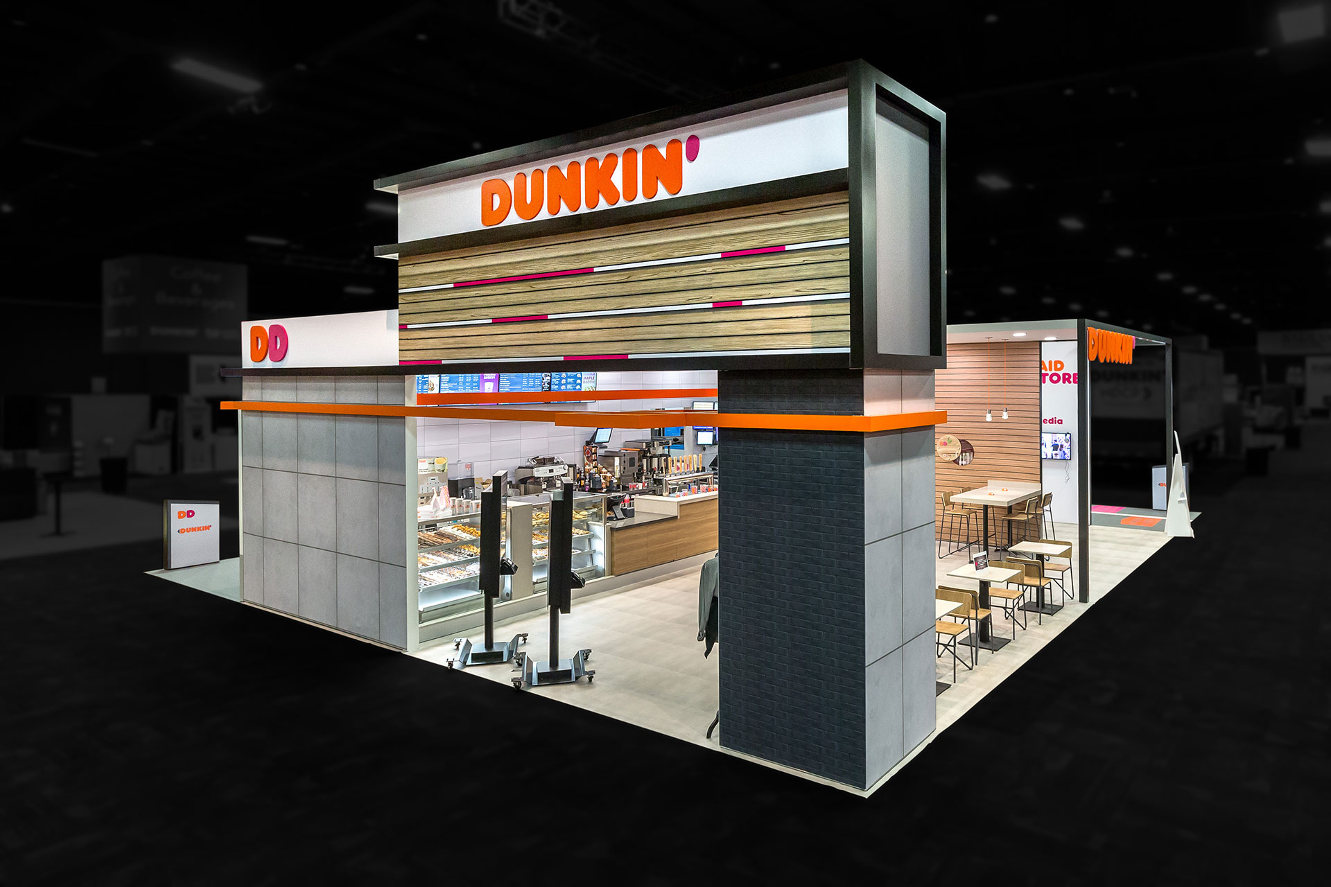 A trade show exhibit which looks like a Dunkin Donuts store clad in grey bricks and tiles and showing the interior counter, display case, and tables from a high perspective and edited so that the area around the exhibit is black and blurred.